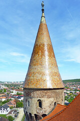 Upper part of The Buzdugan Tower at Corvin Castle: high cone-shaped tiled roof with a statue of a...