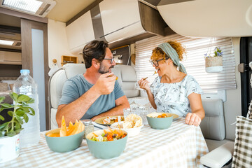 A happy couple spending time together having fun during lunch inside a camper. People with campers...