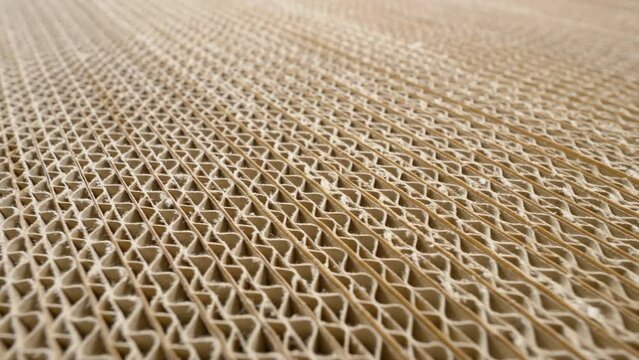 Corrugated cardboard cross section. Camera pans over stacks of folded carton