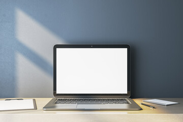 Close up of empty white computer monitor on simple wooden desk. Blue wall background. Workplace concept. Mock up, 3D Rendering.