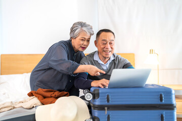 Senior elderly asian couple use laptop for hotel and resort booking online summer holiday travel...
