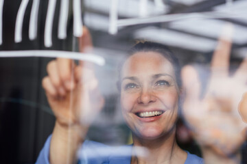 Smiling businesswoman examining graph on glass planning strategy in office