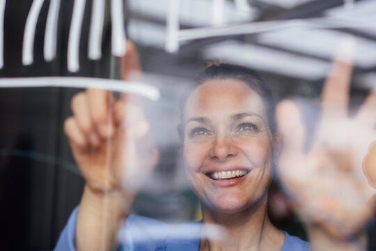 Smiling businesswoman examining graph on glass planning strategy in office