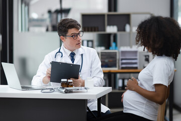 Male doctor examining a pregnant African American woman at the hospital.