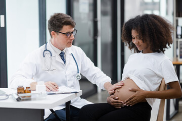 Obraz premium Male doctor examining a pregnant African American woman at the hospital.