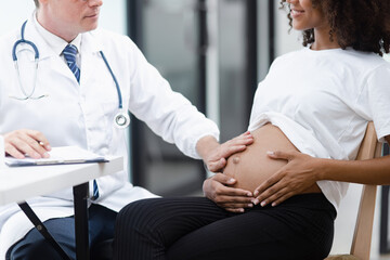 Male doctor examining a pregnant African American woman at the hospital.