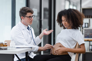 Obraz premium Male doctor examining a pregnant African American woman at the hospital.