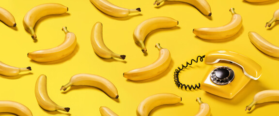 Creative pattern bananas and old yellow phone with hard shadows pattern on yellow background flat...