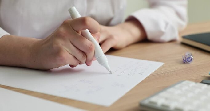 Woman removes wrong text with corrector pen sitting at wooden table slow motion. Employee changes written words. Quick drying liquid eraser
