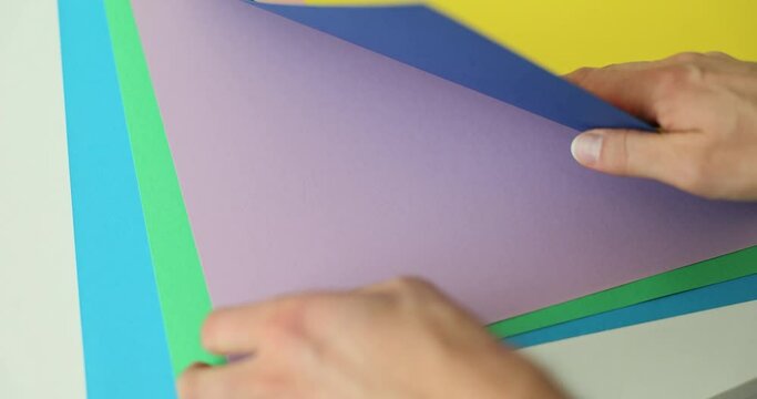 Female designer examines sheets with color gamut samples for home renovation at table. Woman sorts through color options slow motion