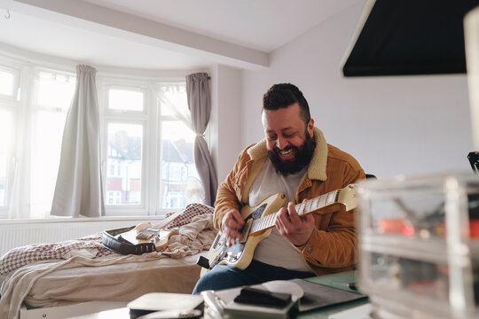 Happy man playing guitar at home