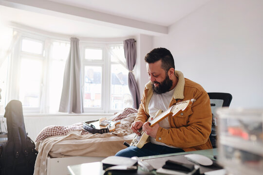 Cheerful guitarist practicing at home