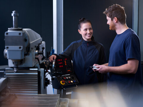 Engineers working on CNC machine at factory