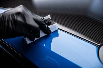 Car cash or car detailing studio worker applying graphene or ceramic coating on blue sport car. - 799869503