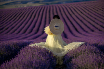 Woman lavender field sunset. Back view woman in yellow dress and hat. Aromatherapy concept, lavender oil, photo session in lavender