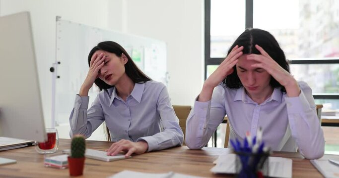 Couple of office workers looks at computer and covers faces with palms getting rejection message. Ashamed employees in cause of deal failure slow motion