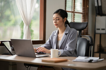 Asian business woman working on computer looking at documents at office