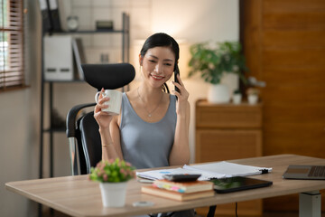 Asian woman talking on the phone, working with customers, office