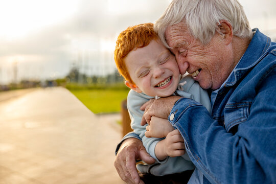 Happy senior man tickling grandson at park