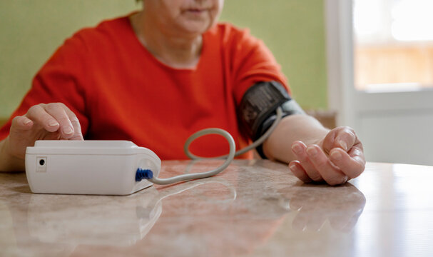 Woman measuring blood pressure using blood pressure monitor at home