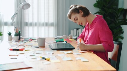 Top view of designer writing idea on colorful sticky notes while sitting at meeting table with...