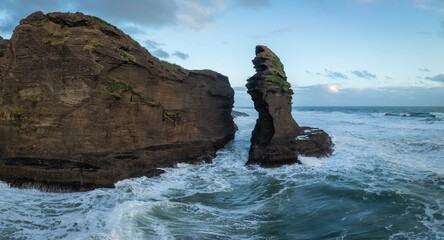 Ocean waves and seafoam crashing over rocks at Piha, Auckland, New Zealand.