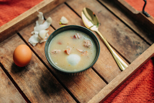 Fresh traditional Polish soup Zurek in bowl on wooden tray