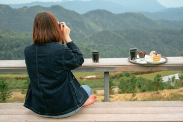 solo asian woman hipster traveler taking photo to mountain at outdoor bar of coffeeshop
