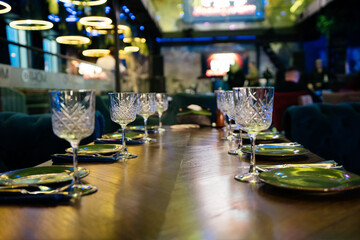 A table with a number of wine glasses and plates. The table is set for a meal. Scene is elegant and sophisticated.