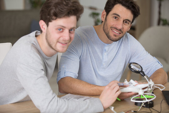 smiling men assembling drone propeller at home