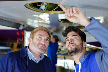 two modern mechanics working in hangar
