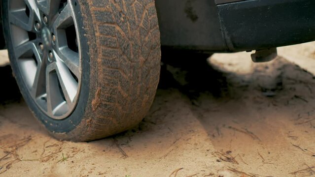 Car wheel struggled to gain traction on sandy road. Vehicle spinning wheel close up. Rotating tyre on dirty road. Automobile offroad