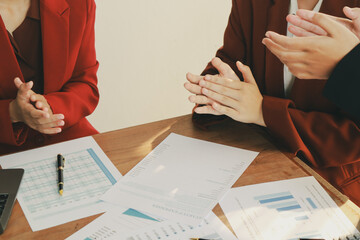 In an office, a woman and a man work together at a desk, using teamwork and communication to...