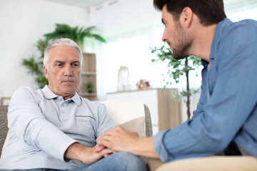 grown up son consoling senior parent