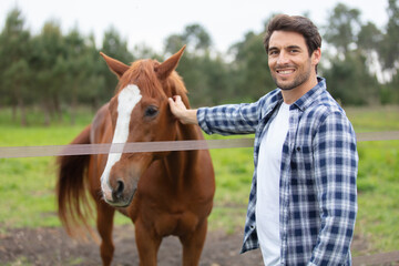 handsome young man taking care of horse