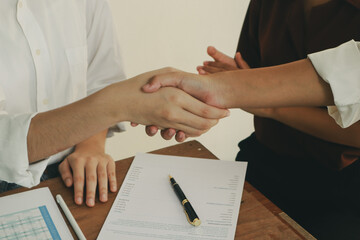 In an office, a woman and a man work together at a desk, using teamwork and communication to succeed in their business meeting.