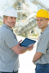 two male engineers holding tablet turning to look at camera