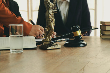 A lawyer prepares for a meeting at their desk, gathering documents and notes. They discuss legal matters, offering guidance and expertise to clients.