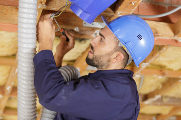 man installing ventilation in ceiling