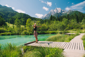 People in nature. Tourist woman with raised arms up in green nature background. View on Zelenci...
