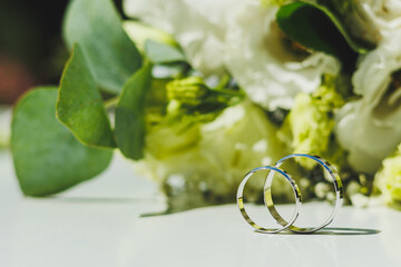 Precious gold rings for newlyweds on a background of flowers. Wedding rings for a couple.