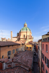An elevated perspective captures the vibrant life of Bologna Via Pescherie Vecchie, with the Santa Maria della Vita green dome rising among rustic buildings (Vertical photo)