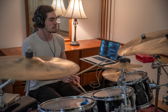 Closeup of drummer in home studio with drum kit and headphones selective focus copy space, cymbals drum kit and laptop