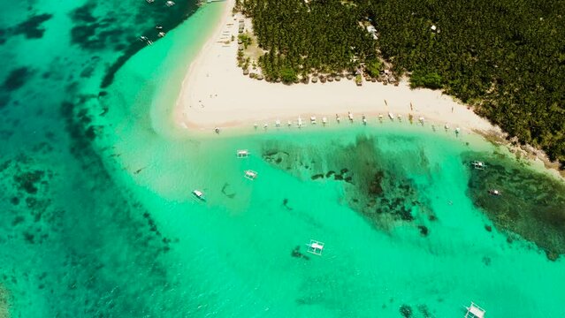 Beach with tourists and boats on a tropical island, clear blue water. Daco island, Philippines. Summer and travel vacation concept