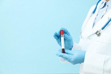 Doctor with test tube with donor blood in hands on blue background, space for text