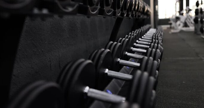 Row of dark dumbbells for pumping muscles in modern gym. Equipment for athletes. Concept of training and improving physical health
