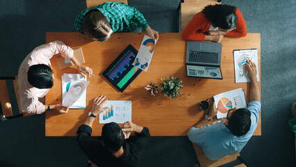 Top down view of manager holds tablet display increasing sales and placed on meeting table. Group...