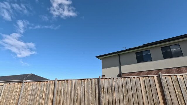Modern residential suburban houses stand behind wooden garden fences in an Australian neighborhood. Concept of neighbors, housing market, real estate investment, the privacy of private property.