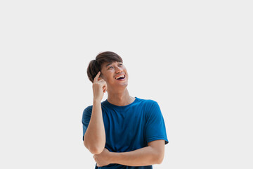 A young Asian man in his 20s wearing a blue t-shirt using my mind to come up with a business idea isolated on a gray background. Concept of using ideas or coming up with new ideas