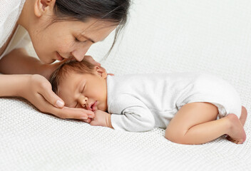 Baby Head in Mother Hands. Happy Mum holding Newborn sleeping on White Blanket. Child Birth and...